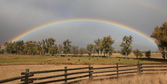 rainbow over a split rail fence ranch in bitterroot valley montana